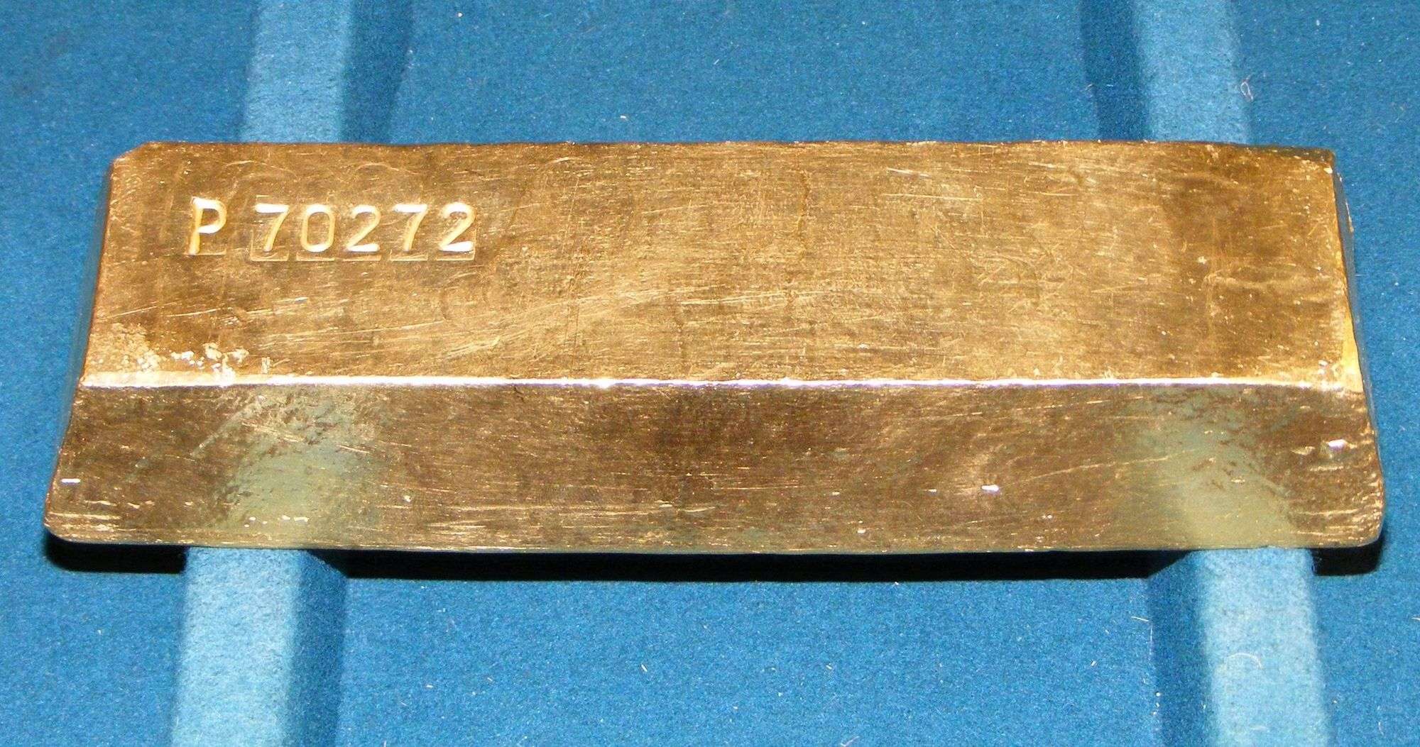 Lingote de oro rectangular con el número P 70272 grabado, sobre un fondo de terciopelo azul