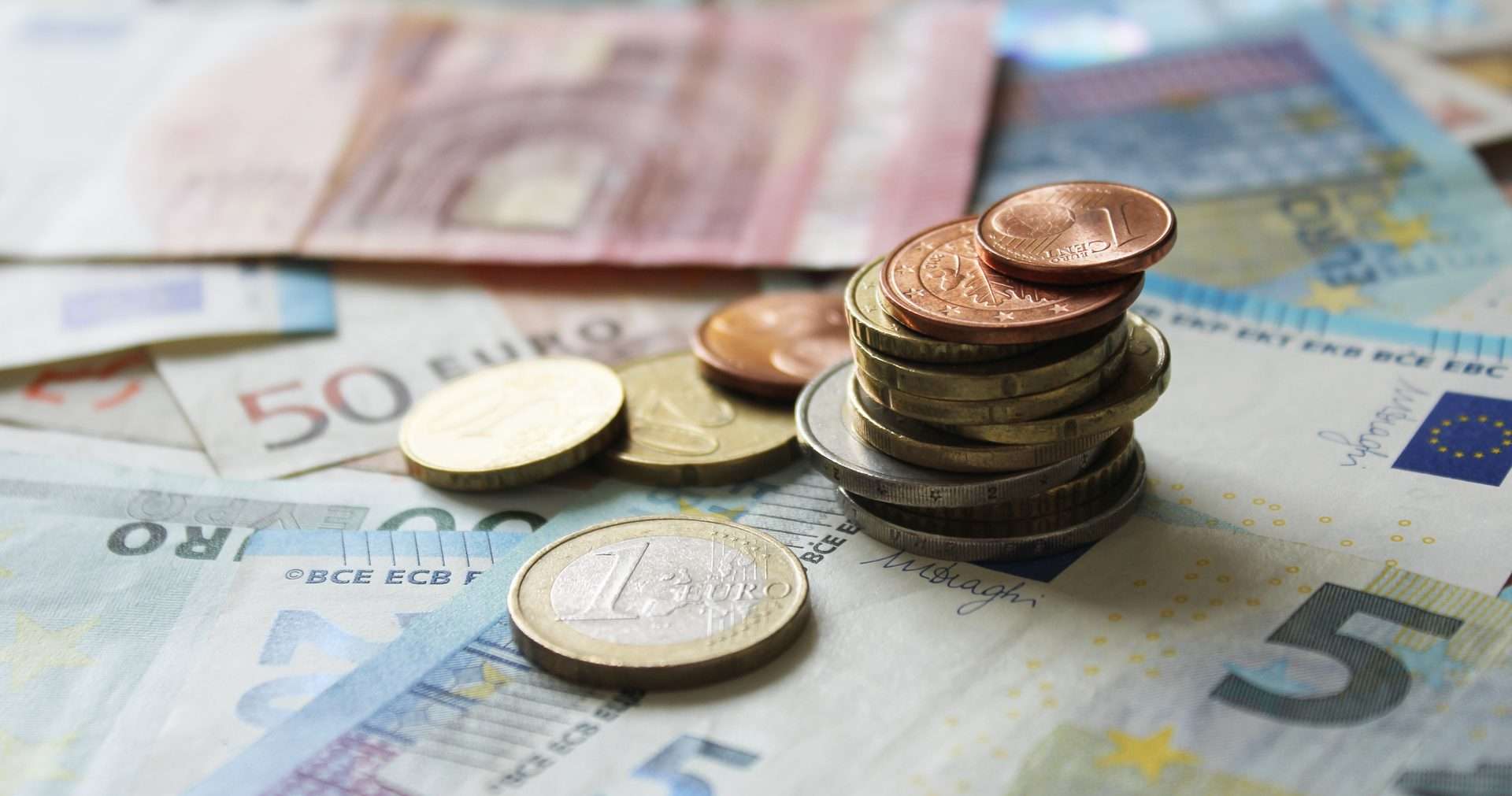 Monedas de euro apiladas sobre billetes de 5, 10 y 50 euros